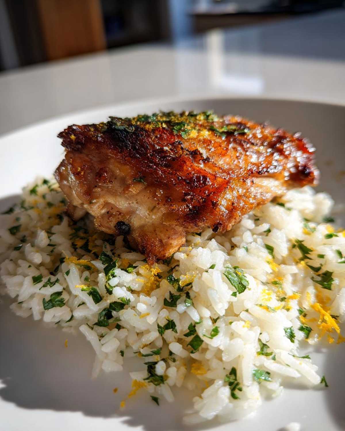 A piece of perfectly browned chicken served over fluffy white rice mixed with parsley and lemon zest in One-Pot Chicken and Rice with Lemon Herbs.