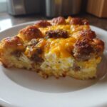 A close-up slice of Tater Tot Breakfast Casserole featuring crispy tater tots, sausage crumbles, and melted cheddar cheese.