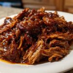 Close-up of shredded pork coated in a rich, glossy sauce, representing Slow Cooker Honey Garlic Pulled Pork.