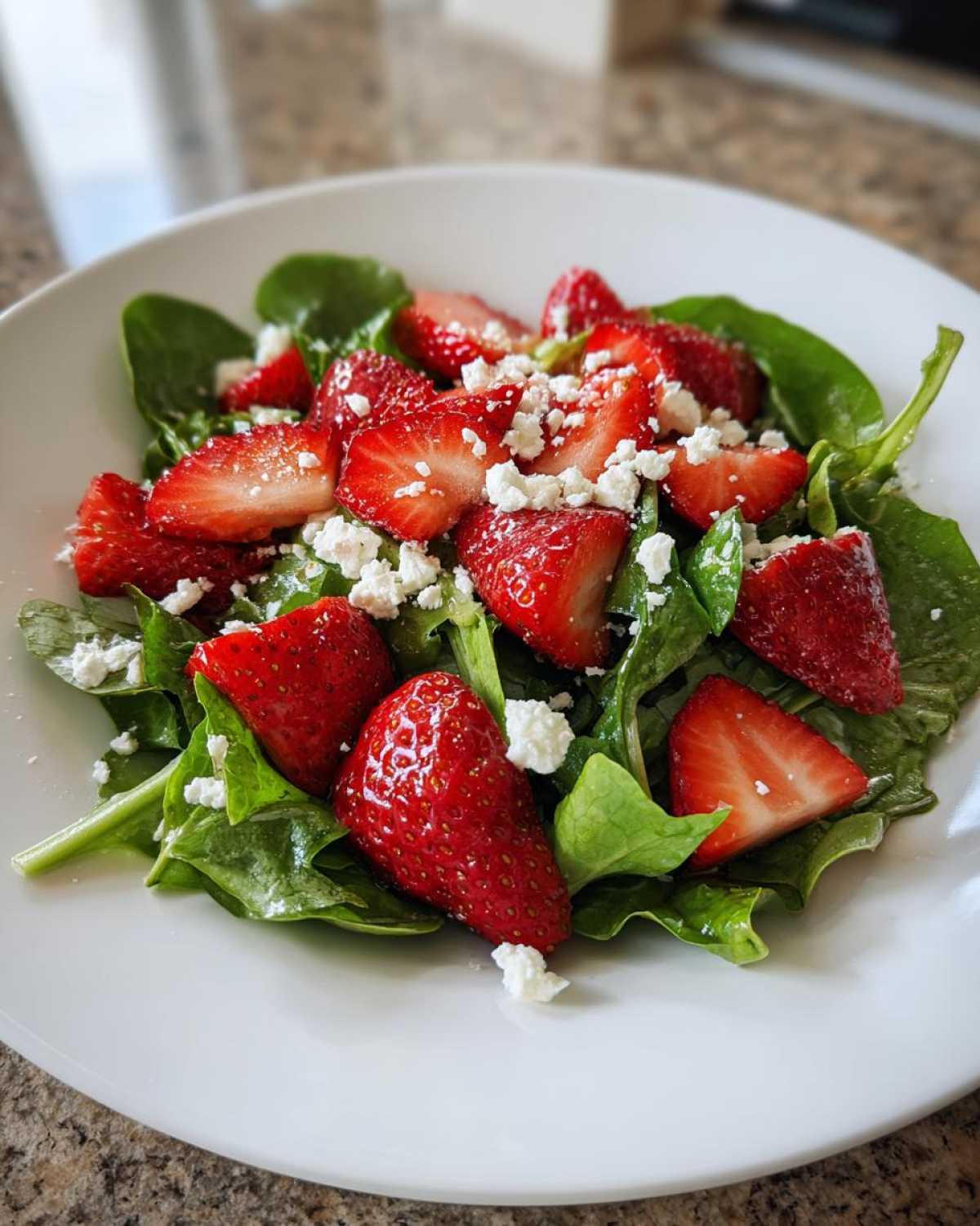 Close-up of a vibrant Spring Mix Salad with Strawberries and Goat Cheese served on a white plate.