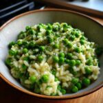 Close-up of creamy Spring Pea and Mint Risotto topped with bright green peas and fresh herbs.