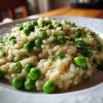 Close-up of creamy Spring Pea and Mint Risotto served on a white plate, garnished with bright green peas and fresh mint.