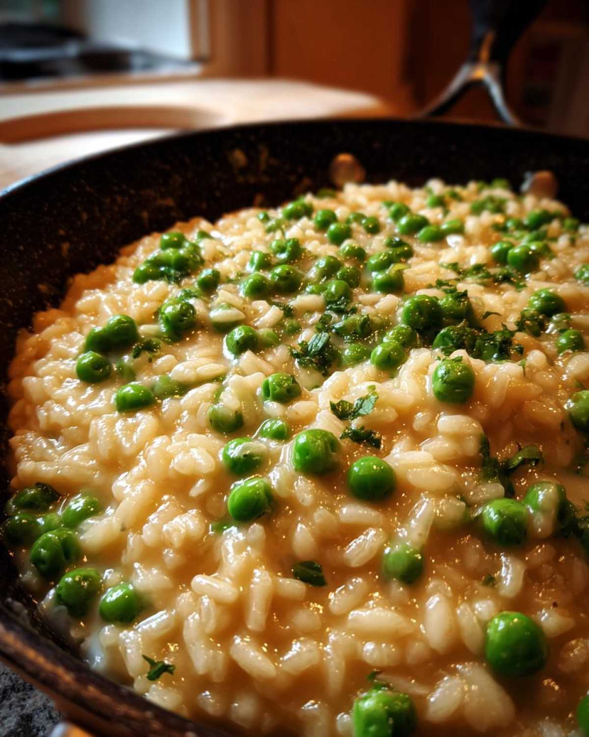 Close-up of creamy Spring Pea and Mint Risotto topped with bright green peas and chopped mint in a black skillet.