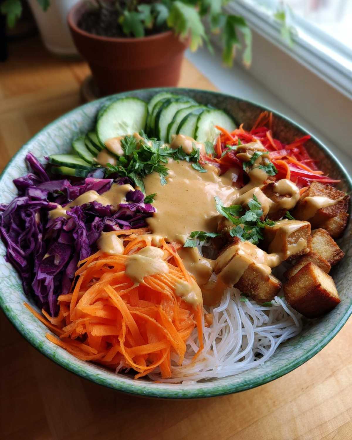 A colorful Spring Roll Bowl with Peanut Sauce featuring rice noodles, crispy tofu, shredded carrots, cabbage, and cucumber.