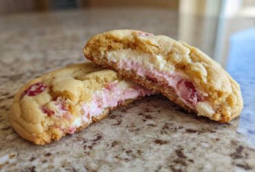 Close-up of Strawberry Cheesecake Stuffed Cookies cut in half showing the creamy pink and white filling.