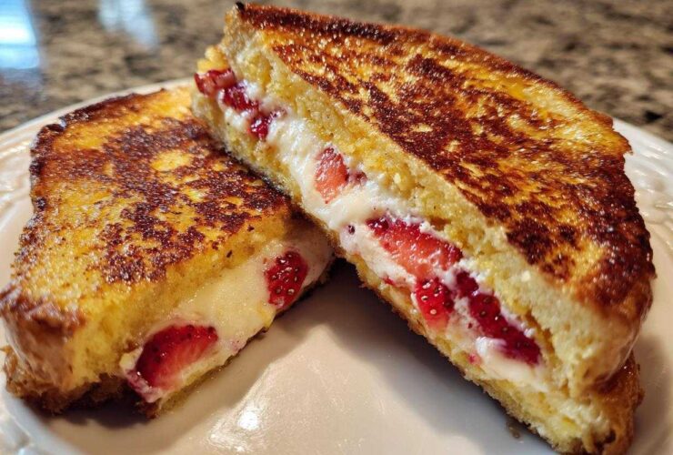 Two halves of golden brown Strawberry Cream Cheese Stuffed French Toast showing the creamy filling and sliced strawberries.