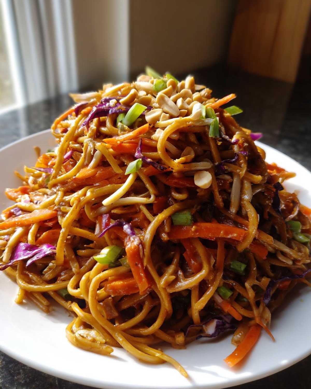A generous serving of glossy Thai Peanut Noodles with Crunchy Veggies, topped with peanuts and scallions.