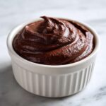A close-up of rich, dark Vegan Chocolate Avocado Mousse swirled high in a white ceramic ramekin.