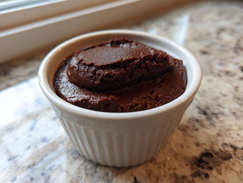 A close-up of rich, dark Vegan Chocolate Avocado Mousse served in a small white fluted ramekin.