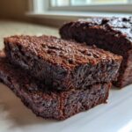 Close-up of moist slices of rich Vegan Chocolate Banana Bread stacked on a white serving platter.