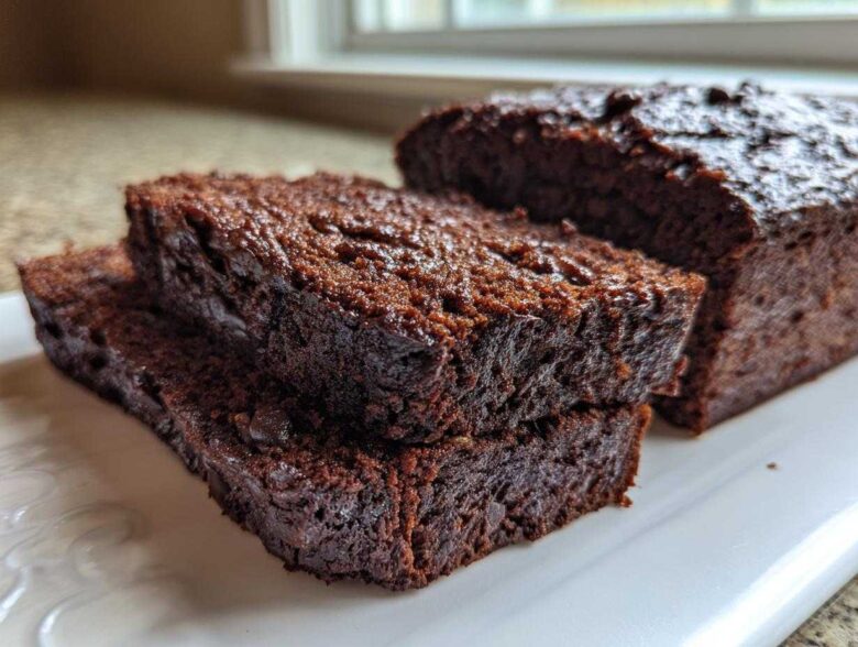 Close-up of moist slices of rich Vegan Chocolate Banana Bread stacked on a white serving platter.