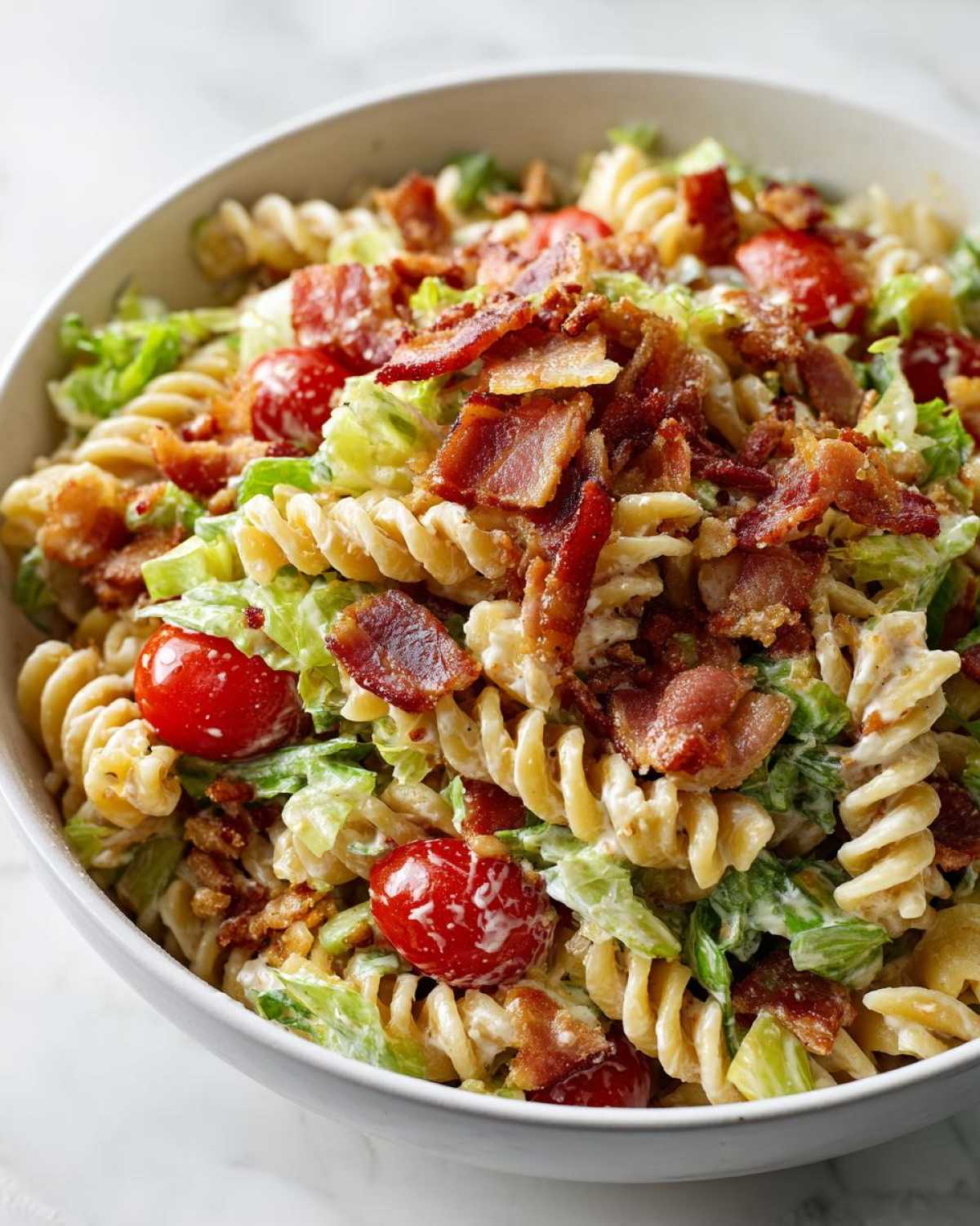 A close-up of creamy BLT Pasta Salad with Ranch featuring rotini pasta, chopped lettuce, cherry tomatoes, and crispy bacon.
