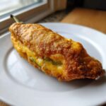 A single, perfectly fried Chiles Rellenos Stuffed Poblanos, showing a golden, crispy batter and melted cheese filling.