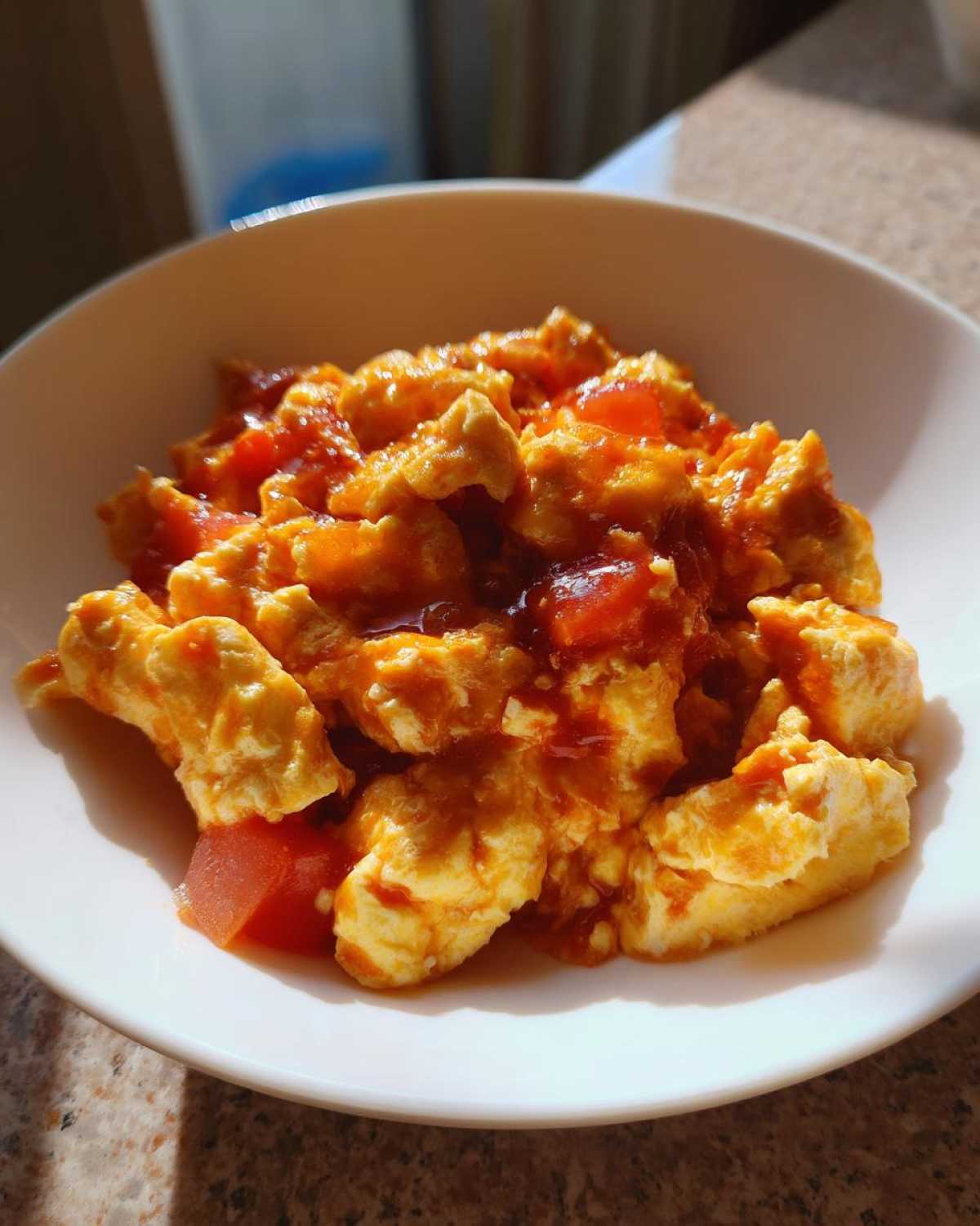 A close-up bowl filled with fluffy scrambled eggs coated in a rich, savory tomato sauce, showcasing the Chinese Tomato Egg Stir-Fry.