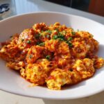 A close-up of rich, saucy Chinese Tomato Egg Stir-Fry garnished with chopped green onions.