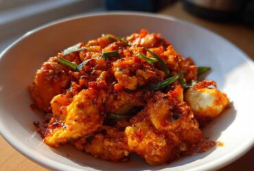 Close-up of vibrant, saucy Chinese Tomato Egg Stir-Fry garnished with green onions in a white bowl.