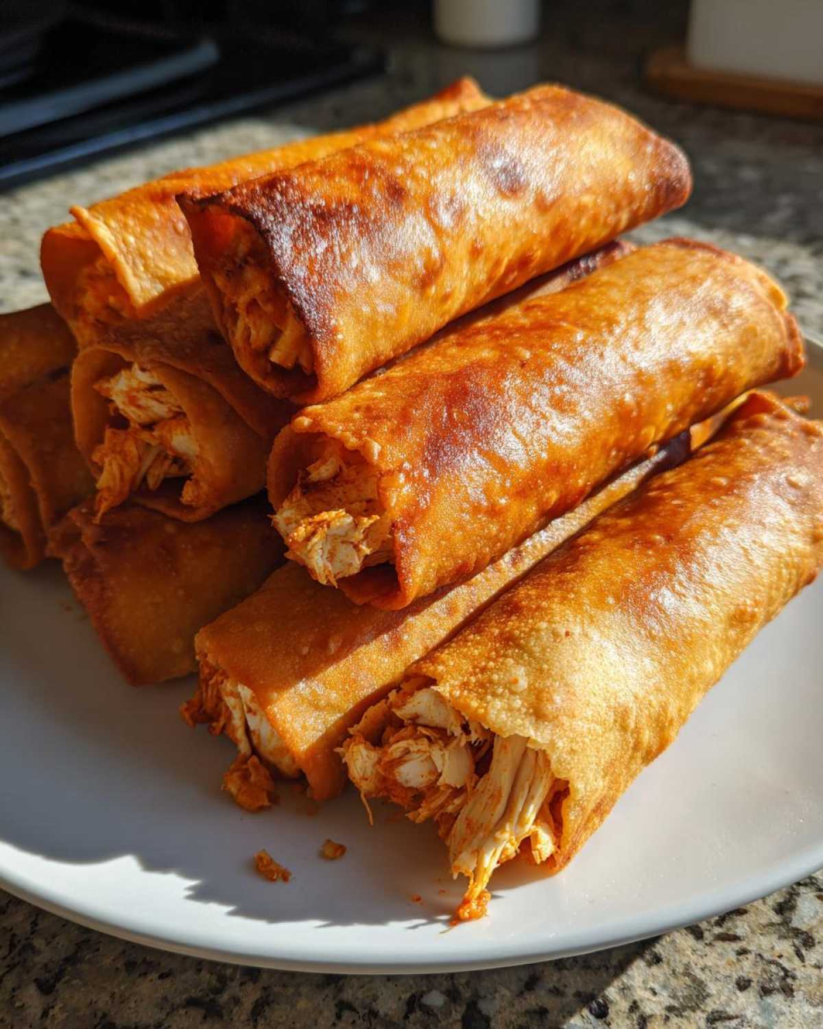 A stack of golden brown, crispy Chipotle Chicken Taquitos Baked Crisp showing shredded chicken filling spilling out slightly.