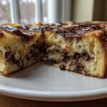 Close-up of Chocolate Chip Brioche Toast cut in half, showing melted chocolate chips inside and chocolate drizzle on top.