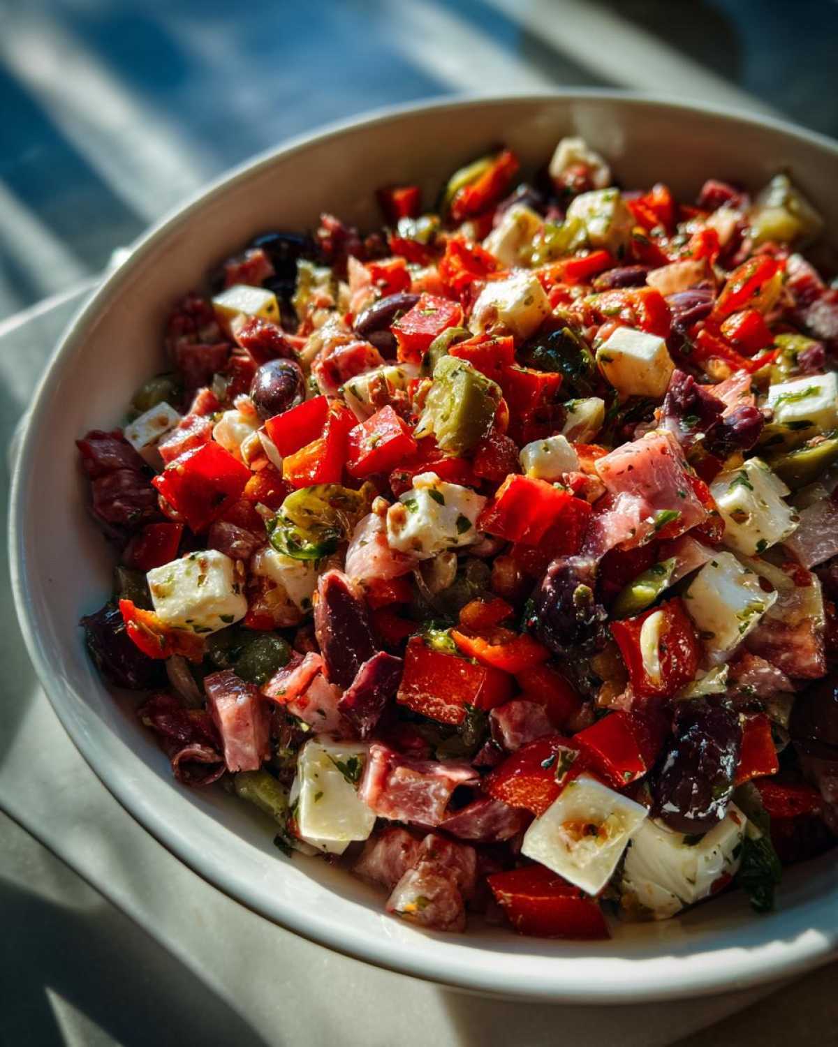 Close-up of a vibrant Chopped Italian Antipasto Salad featuring cubes of cheese, red peppers, olives, and cured meats.