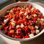 Close-up of a bowl filled with colorful Chopped Italian Antipasto Salad featuring diced meats, cheese cubes, peppers, and olives.