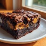 Close-up of a fudgy Dulce de Leche Brownie Bar showing the gooey caramel swirl inside, served on a white plate.