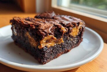 Close-up of a fudgy Dulce de Leche Brownie Bar showing the gooey caramel swirl inside, served on a white plate.