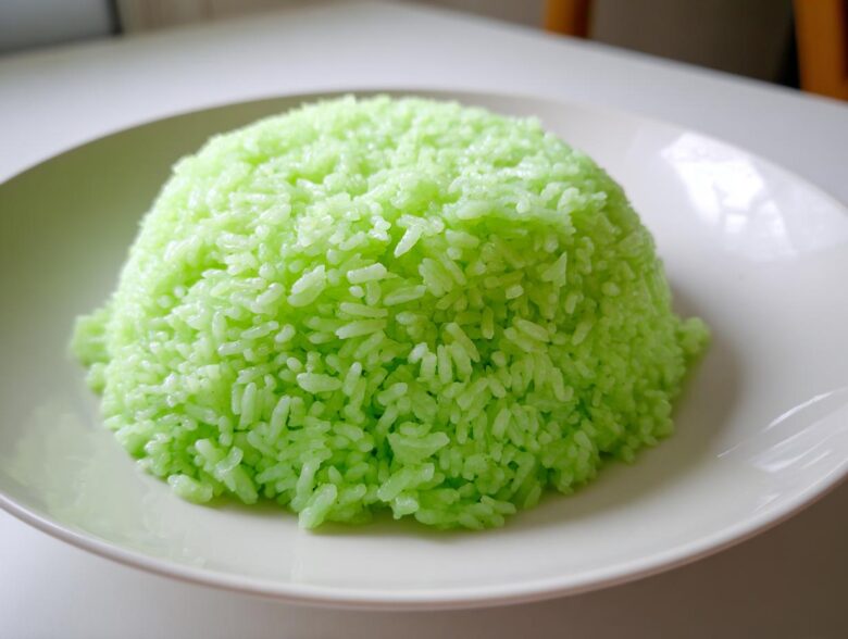 A perfectly molded mound of bright green Pandan Coconut Rice served on a white plate.