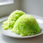 Two mounds of bright green, fluffy Pandan Coconut Rice served on a white plate.