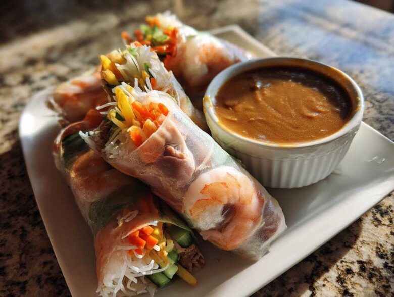 A plate of vibrant Fresh Spring Rolls with Peanut Sauce, showing shrimp and colorful vegetables wrapped in rice paper.