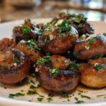 Close-up of glossy, sautéed Garlic Butter Mushrooms with Thyme and chopped parsley on a white plate.