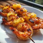 Close-up of perfectly grilled pineapple shrimp skewers with caramelized edges served on a white plate.