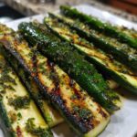Close-up of perfectly grilled zucchini with lemon herb marinade, showing distinct grill marks.