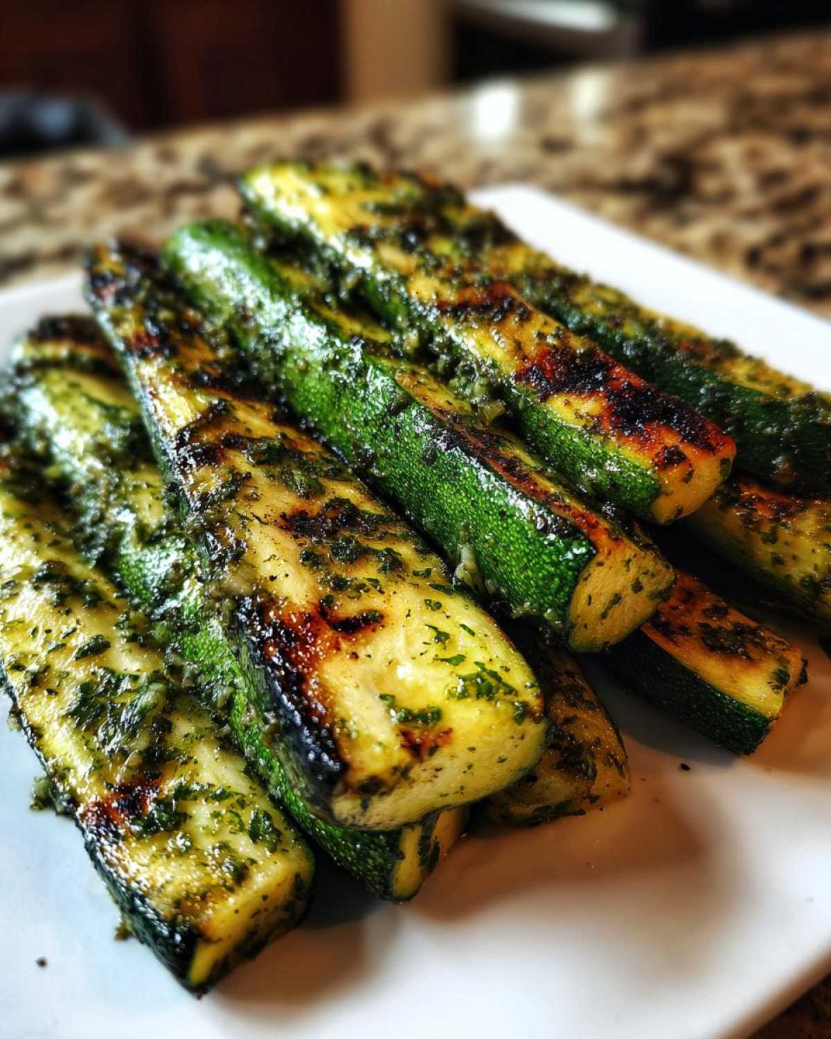 Close-up of perfectly Grilled Zucchini with Lemon Herb Marinade, showing char marks and vibrant green herbs.