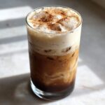 A tall glass of Horchata Iced Coffee Refresher topped with creamy foam and cinnamon.