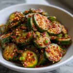 Close-up of vibrant Korean Cucumber Salad Oi Muchim, featuring sliced cucumbers coated in spicy red chili flakes and sesame seeds.