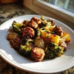 A serving of Lemon Herb Sausage Sheet Pan Dinner featuring browned sausage pieces, roasted broccoli, and potatoes on a white plate.
