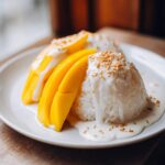 Close-up of perfectly molded Mango Sticky Rice with Coconut, topped with sesame seeds.
