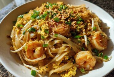 Close-up of a delicious plate of Pad Thai with Tamarind Sauce, featuring shrimp, scrambled egg, and crushed peanuts.