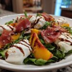 A vibrant Peach Burrata Prosciutto Salad featuring fresh burrata, prosciutto slices, peach wedges, and arugula drizzled with balsamic glaze.