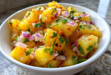 Close-up of vibrant Pineapple Habanero Salsa featuring chunks of pineapple, red onion, and cilantro in a white bowl.