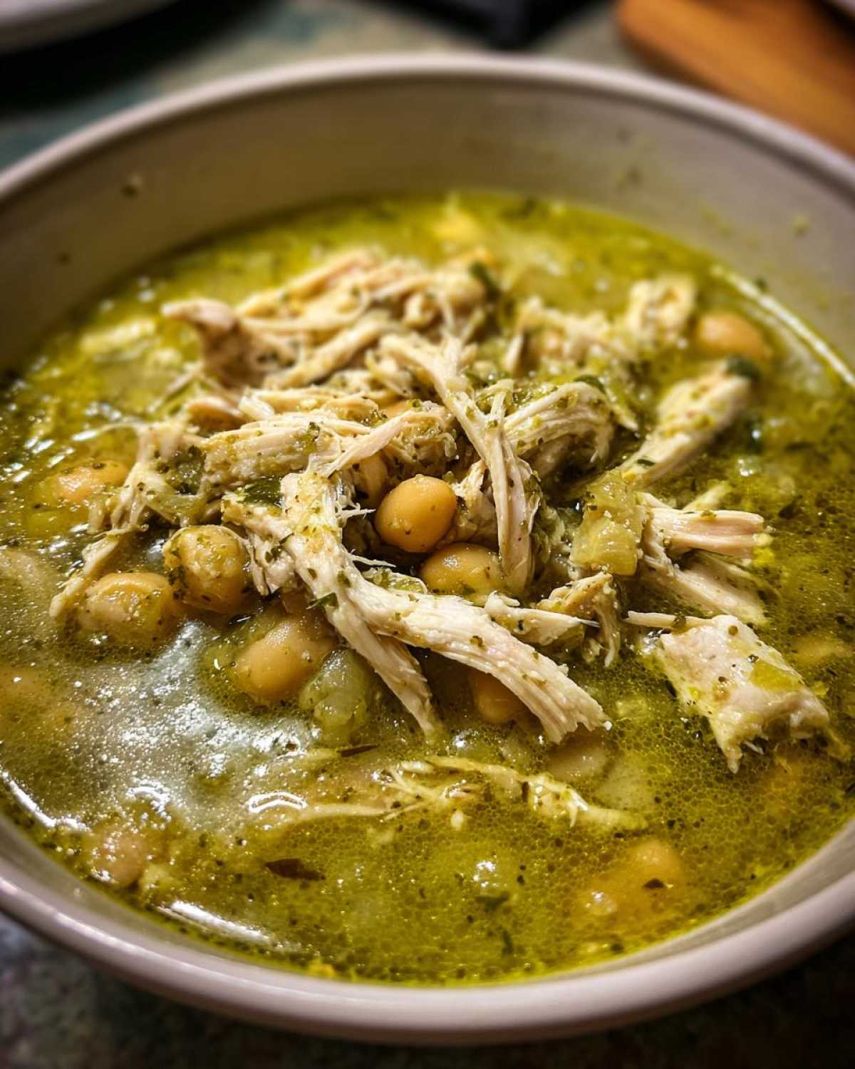 Close-up of a hearty bowl of Pozole Verde Chicken Soup topped with shredded chicken and hominy.