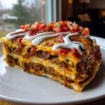 A thick, layered slice of Refried Bean Crunchwrap Skillet topped with melted cheese, salsa, and sour cream.
