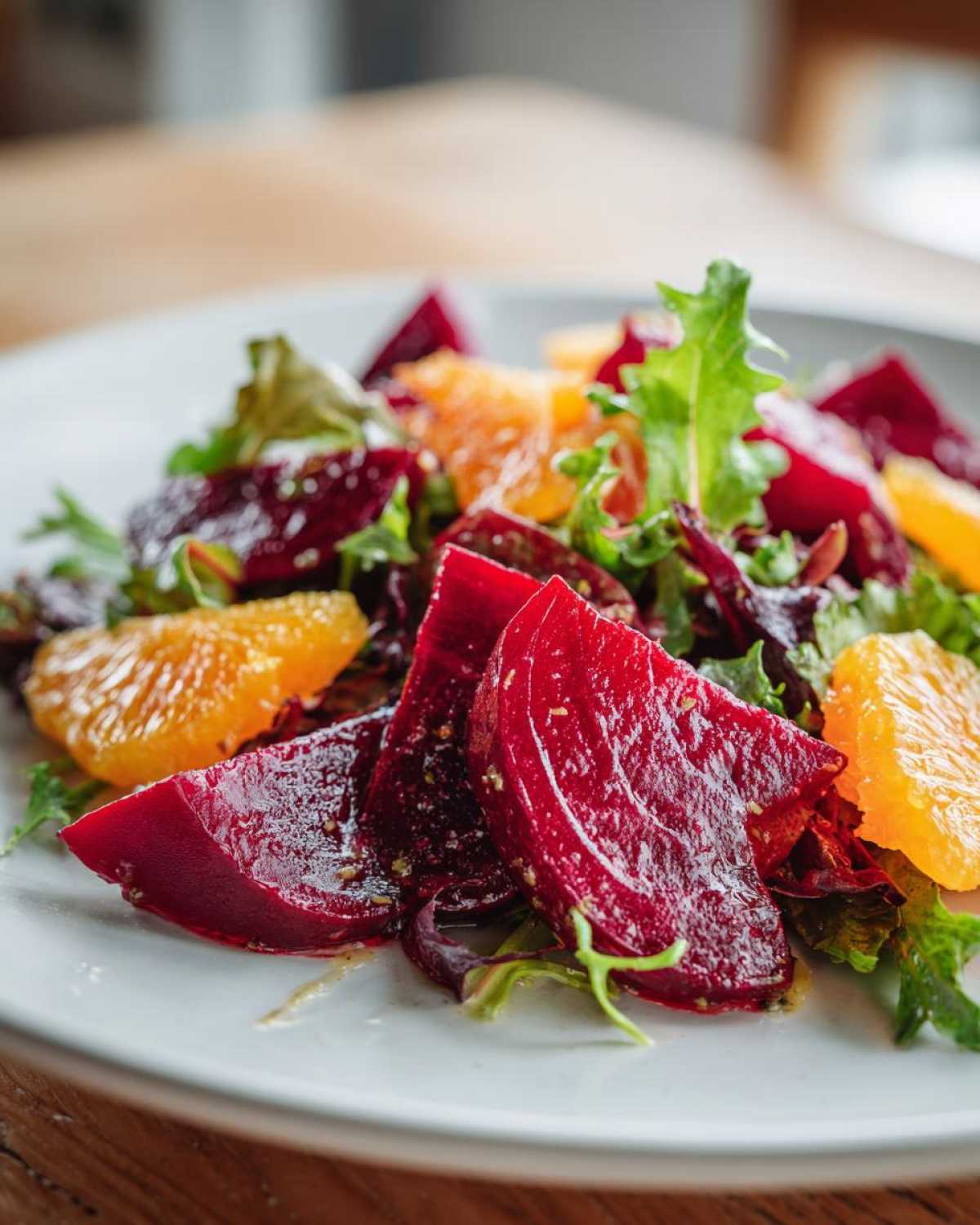 Close-up of a vibrant Roasted Beet Orange Salad featuring deep red beet wedges, bright orange segments, and mixed greens.