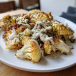 Close-up of perfectly Roasted Cauliflower with Tahini Lemon sauce drizzled over charred florets on a white plate.