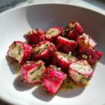 Close-up of vibrant Roasted Radishes with Garlic and Dill, glistening with oil, served in a white bowl.