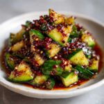 Close-up of vibrant Sichuan Smash Cucumber Salad coated in spicy chili oil and flakes.