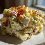 A mound of creamy Smoked Paprika Potato Salad featuring potatoes, celery, red onion, and egg, topped with paprika.
