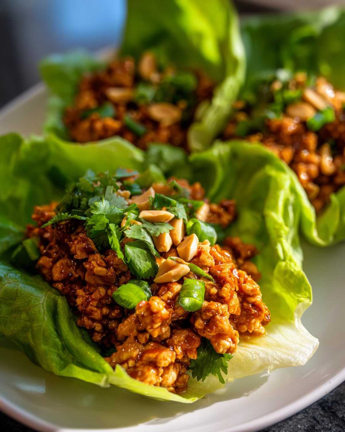 Close-up of Spicy Peanut Chicken Lettuce Cups filled with savory chicken mixture, topped with peanuts and cilantro.