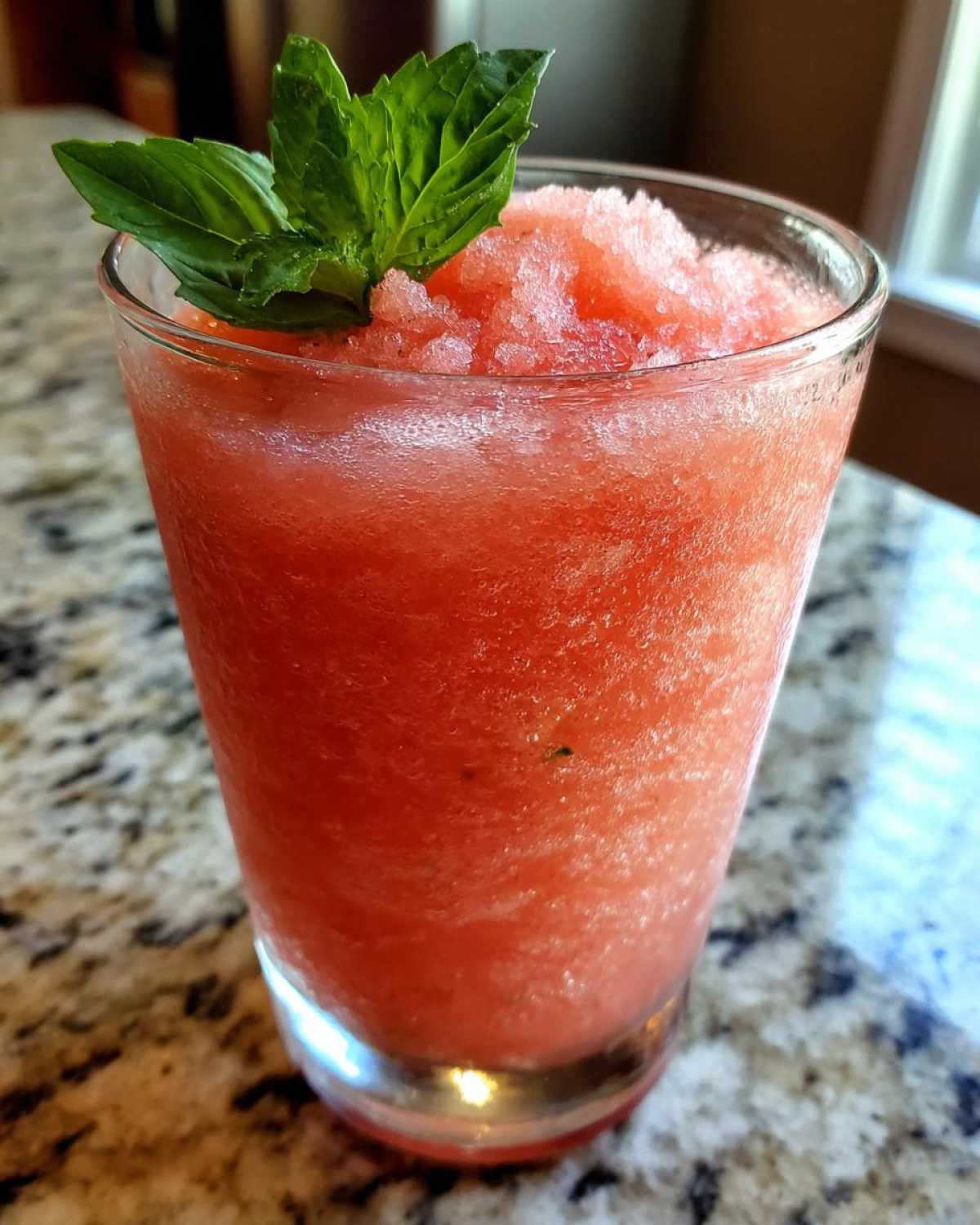 Close-up of a refreshing Strawberry Basil Lemonade Slush topped with fresh basil leaves.