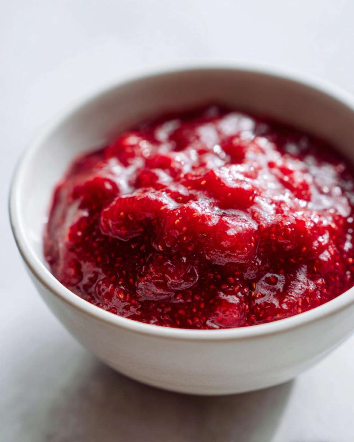 A close-up of vibrant, chunky 10-Minute Strawberry Chia Jam served in a small white bowl.
